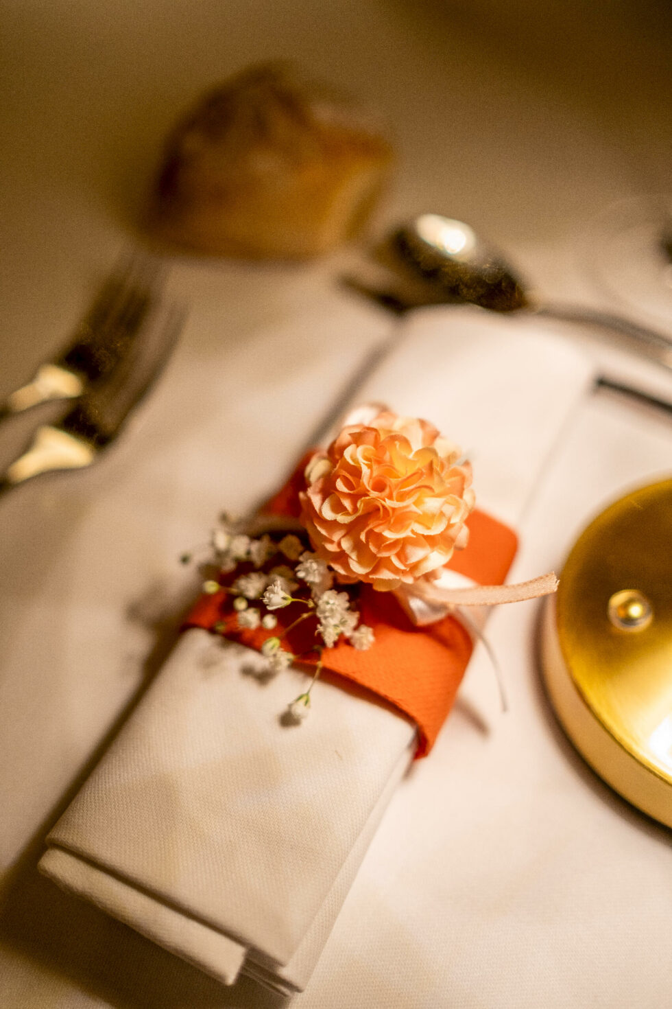 Détail de décoration de table avec serviette, fleur orange et ambiance de réception élégante