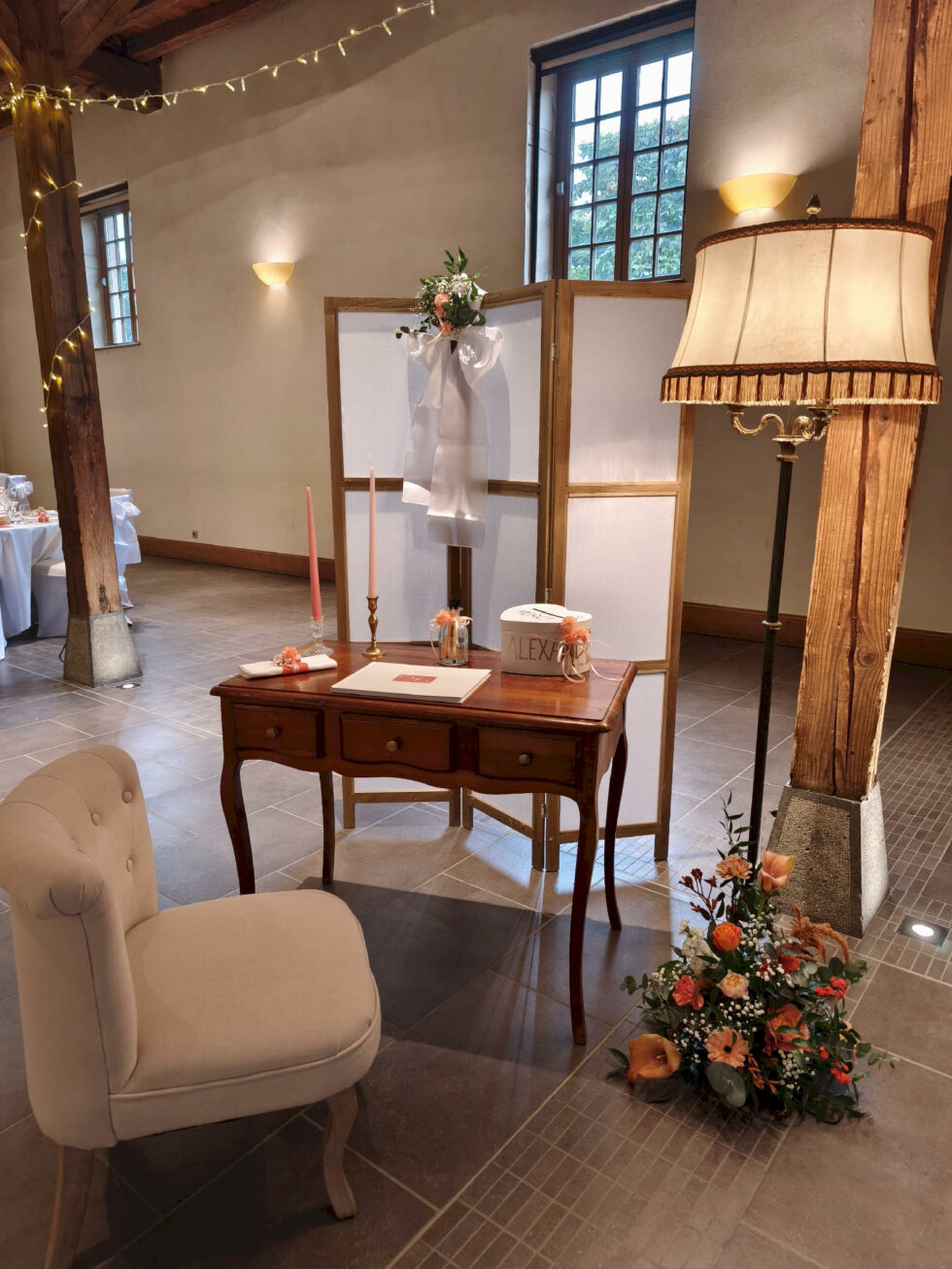 Espace livre d’or avec mobilier vintage, lampe et décoration florale pour mariage