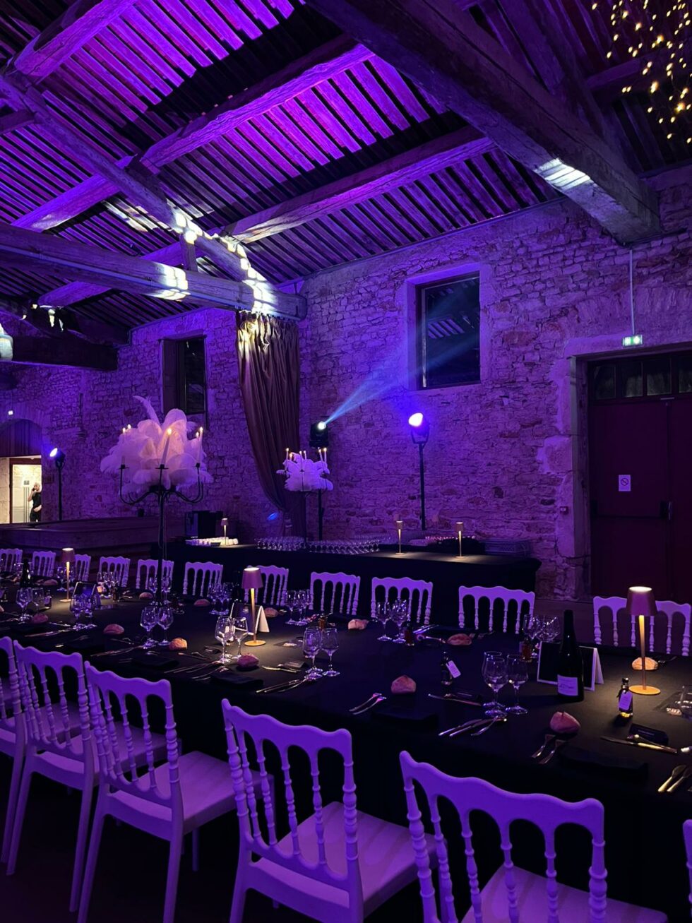 Mise en ambiance lumineuse violette dans une salle de réception avec grandes tables et chaises napoléon