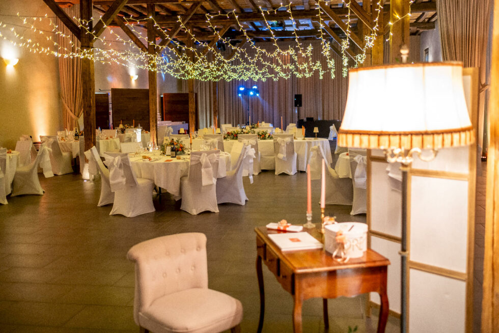 Salle de réception avec guirlandes lumineuses, tables dressées et espace livre d’or