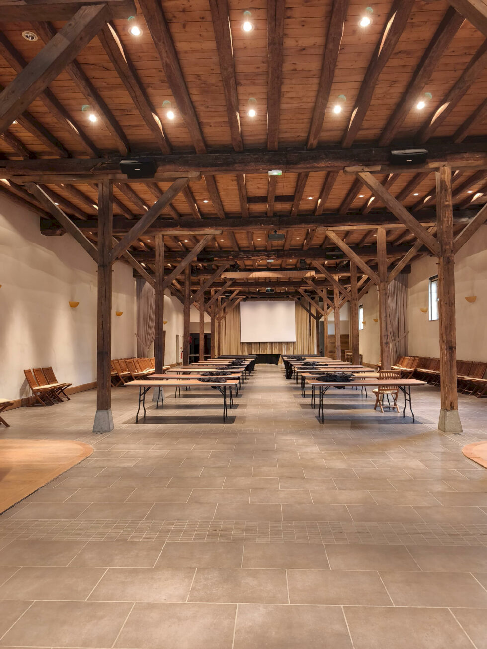 Salle de réception vide avant installation avec charpente bois et tables en préparation