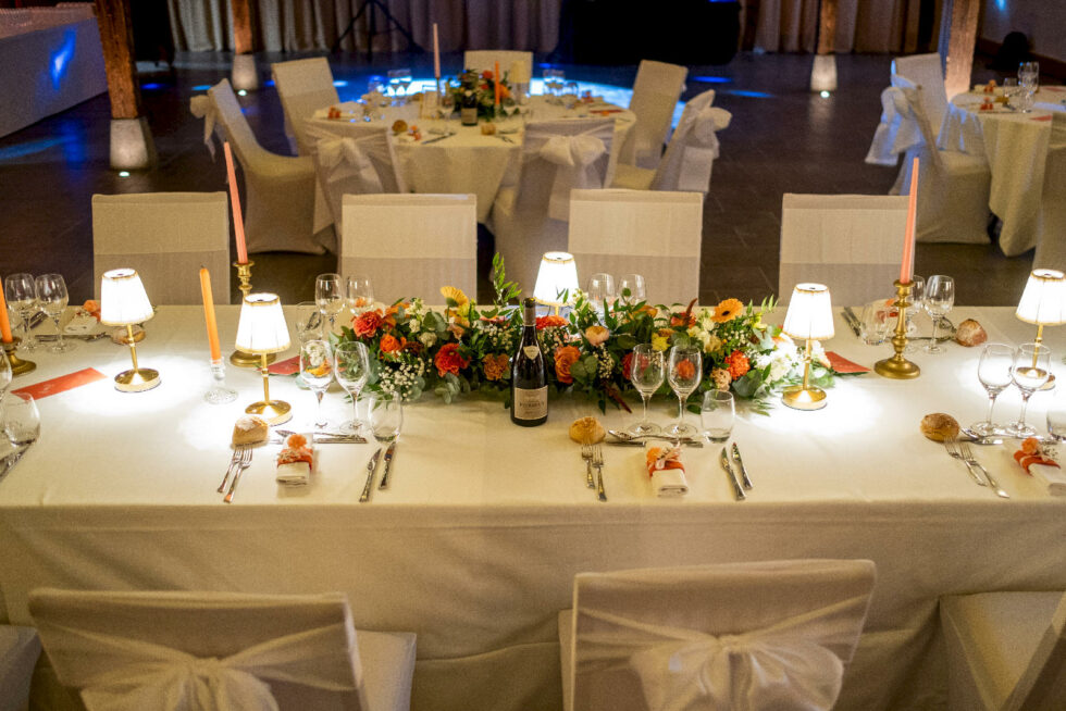 Table d’honneur décorée avec fleurs, bougies et mobilier de réception pour mariage