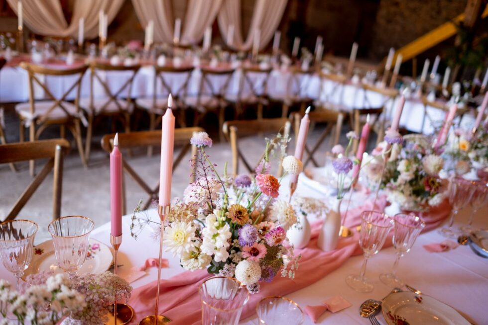 Centre de table mariage avec fleurs champêtres pastel et bougies roses sur table décorée